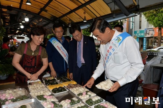 광주시 남구가 전통시장에 활력을 불어넣기 위해 '2018년 설맞이 전통시장 가는 날'을 운영한다. 최영호 남구청장(오른쪽 끝)이 지난해 추석을 앞두고 '추석맞이 전통시장 가는 날' 행사에서 시장에 방문해 떡을 고르고 있다./ 사진=남구청 제공