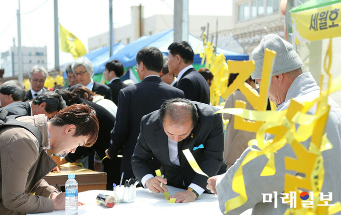 장휘국 광주시 교육감이 세월호 참사 4주기를 맞아 리본에 추모의 글을 작성하고 있다. / 사진=광주시교육청 제공