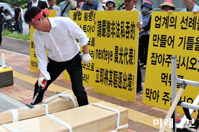 김영석 HS글로벌 대표가 11일 넥스트아이 본사 앞에서 준비해온 2개의 관을 망치로 부수고 있다./사진=김정현 기자