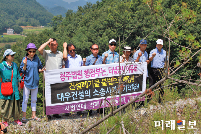 지난 7월 17일 대우건설이 충주-제천간 동서고속도로 건설공사(제3공구) 과정에서 운영했던 충주시 산척면 산 42번지 소재 사토장에서 법원 감정인에 의한 현장 감정이 진행된 가운데 조남숙 사법정의국민연대 단장을 비롯 적폐청산행동연대 회원들이 "청주법원 행정부는, 터널공사 이유로 건설폐기물 불법으로 매립한 대우건설의 소송사기를 기각하라!"라고 외치고 있다./사진=장건섭 기자
