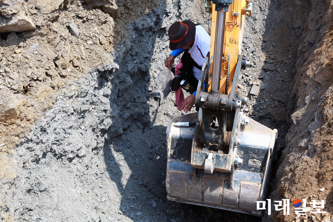 지난 7월 17일 대우건설이 충주-제천간 동서고속도로 건설공사(제3공구) 과정에서 운영했던 충주시 산척면 산 42번지 소재 사토장에서 법원 감정인에 의한 현장 감정이 진행된 가운데 매립장 굴착 과정에서 숏크리트색을 띤 흙이 발견되자 법원 감정인이 시료를 채취하고 있다./사진=장건섭 기자