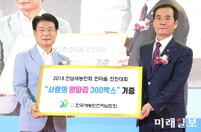 새 농민회 김안석 전남회장이 이승옥 강진군수에게 사랑의 양파즙을 전달하고 있다. / 사진=강진군 제공