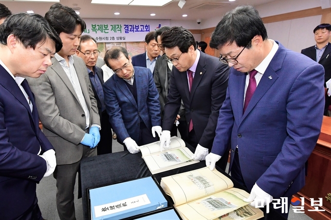 염태영수원시장(오른쪽 끝), 안민석 의원(오른쪽 두번째), 이한규 제1부시장(왼쪽 끝)이 관계자들과 함께 한글본 '정리의궤' 복제본을 살펴보고 있다./사진=수원시 제공