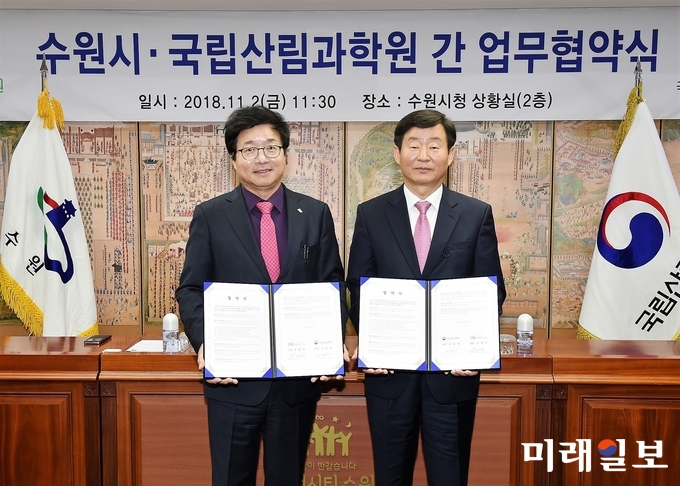 염태영 수원시장(왼쪽)과 이창재 국립산림과학원장(오른쪽)이 ‘미세먼지 저감 및 무궁화 사업 성공을 위한 업무협약’을 체결하고 기념촬영을 하고 있다./사진=수원시 제공