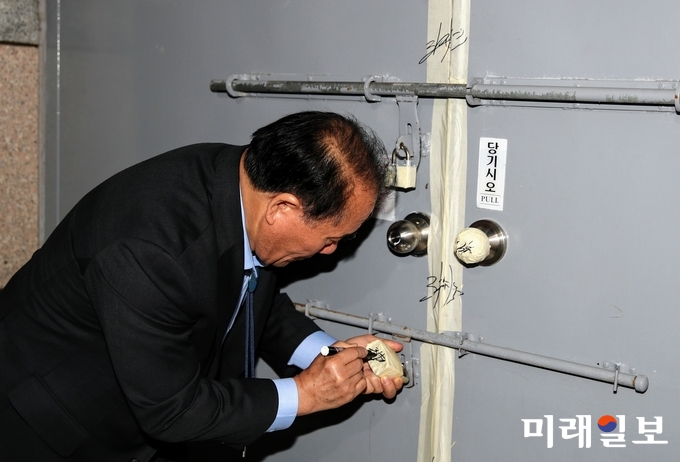장휘국 교육감이 13일 입고된 2019학년도 대학수학능력시험 문답지를 점검하고 봉인한 가운데 서명을 하고 있다. / 사진=광주시교육청 제공