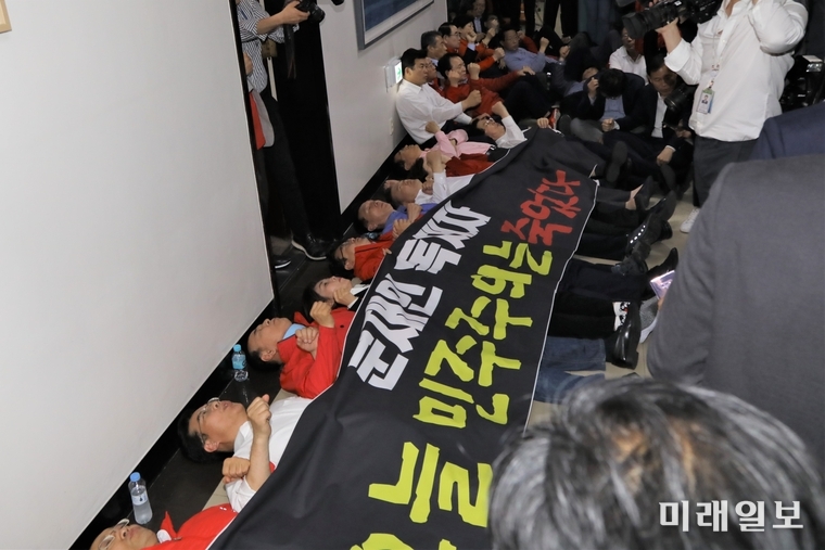 자유한국당 의원들이 30일 새벽 국회 사법개혁특별위원회의 공수처 설치법과 검경수사권 개정안 지정 처리에 대해 '문재인 독재자, 오늘 민주주의는 죽었다'는 문구가 적힌 검은 프랭카드를 두르고 바닥에 누워 항의하고 있다./사진=김정현 기자