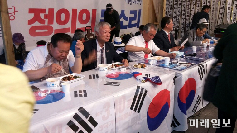 지난 8일 오후 서울 세종로 광화문광장에 불법으로 설치되어 있는 대한애국당 천막 농성장에서 (사진 왼쪽부터) 박태우 사무총장, 서석구 변호사(대한애국당 산하 천만인무죄석방본부 공동대표), 허평환 전 기무사령관, 조원진 대표 등이 심야 3인 긴급 합동 간담회에 앞서 태극기가 깔려있는 테이블 위에 음식물 놓고 저녁식사를 하고 있다./사진=구경옥 독자 제공