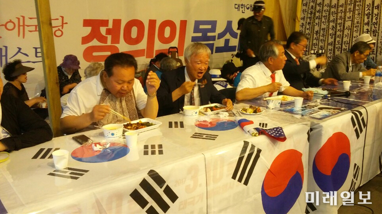 지난 8일 오후 서울 세종로 광화문광장에 불법으로 설치되어 있는 대한애국당 천막 농성장에서 (사진 왼쪽부터) 박태우 사무총장, 서석구 변호사(대한애국당 산하 천만인무죄석방본부 공동대표), 허평환 전 기무사령관, 조원진 대표 등이 심야 3인 긴급 합동 간담회에 앞서 태극기가 깔려있는 테이블 위에 음식물 놓고 저녁식사를 하고 있다./사진=구경옥 독자 제공