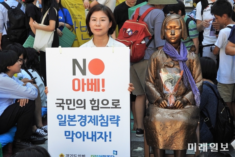 14일 오후 서울 종로구 옛 일본대사관 앞에서 열린 제 1400차 일본군 성노예제 문제 해결을 위한 정기 수요집회에 참석한 한 시민이 평화의 소녀상 옆에서 피켓을 들고 있다./사진=장건섭 기자