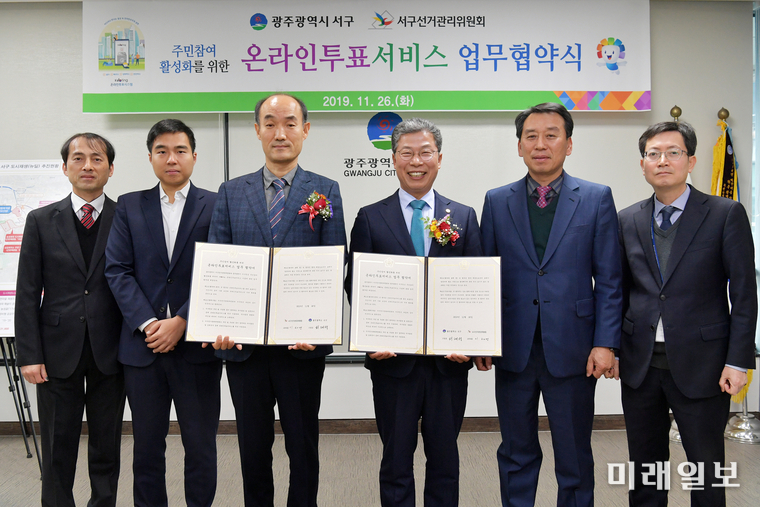 광주 서구 서대석 청장(오른쪽)과 서구선관위 이해영 사무국장이 운라인투표 활성화를 위한 업무협약을 체결하고 기념촬영 하고 있다. / 사진=서구 선관위 제공