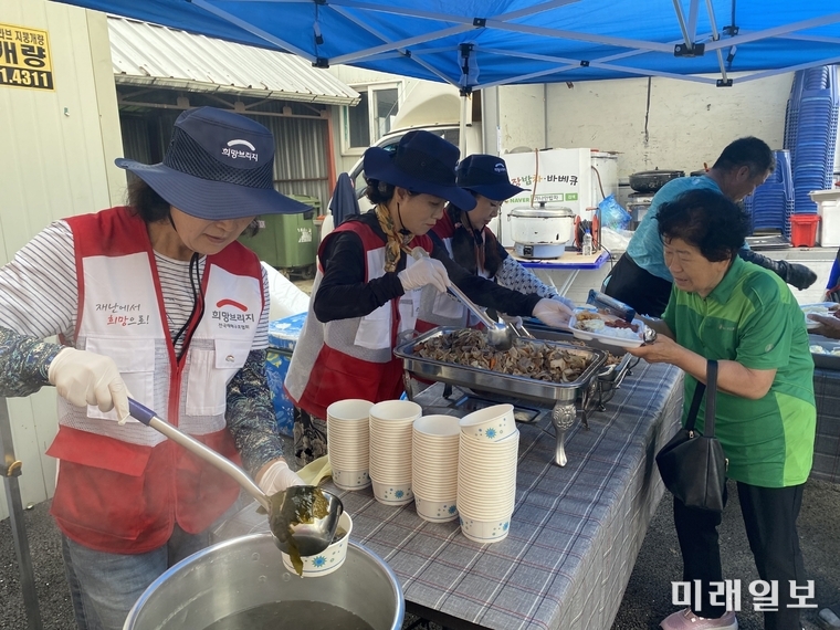 희망브리지 구호 대원들이 21일 수해 현장에서 이재민들에게 식사 봉사를 하고 있다./사진=희망브리지 제공