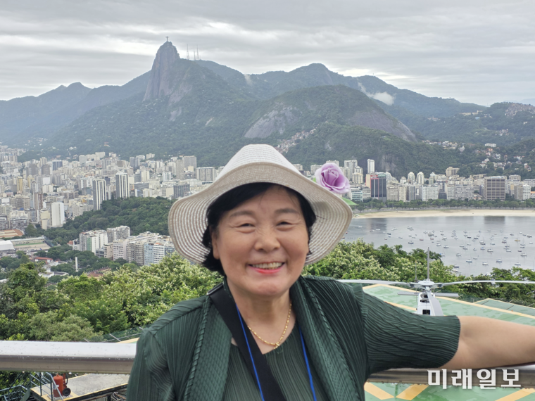 브라질 코바카바나 해변이 한 눈에 보이는 시내 뒤편으로 보이는 코르코바도산 정상의 거대한 '구세주 그리스도상'을 배경으로 김민정 한국문인협회 부이사장이 기념촬영을 하고 있다./사진=김민정 시인 제공