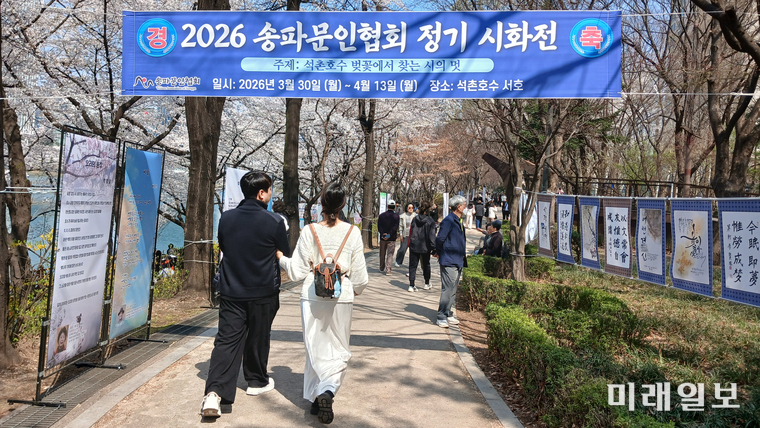 서울 송파구 석촌호수 서호 산책로에서 열린 ‘2026 송파문인협회 정기 시화전’을 찾은 시민들이 벚꽃길을 따라 전시된 시화 작품을 감상하며 봄 정취를 만끽하고 있다./사진=송파문협 제공